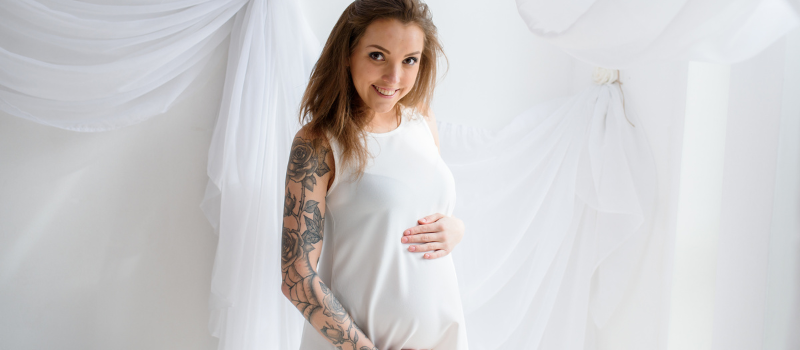 A pregnant woman and man proudly show off her tummy with tattoos. The  modern day mother